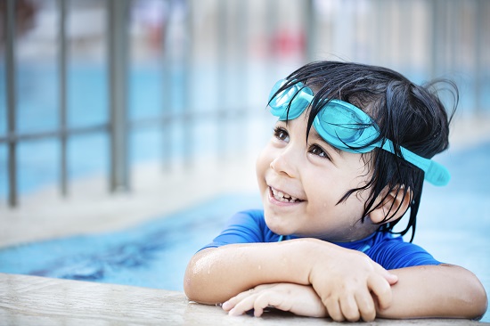 child in swimming pool with goggles 