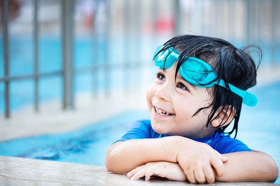 child in swimming pool with goggles